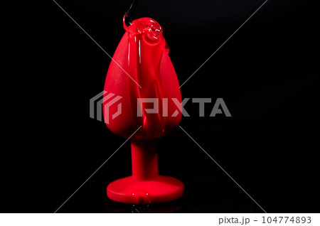 Intimate lubricant pours on a red anal plug on a black background. Copy space.  104774893