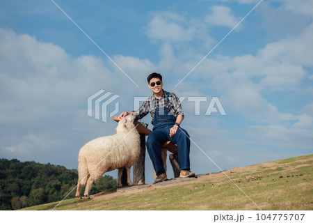 A happy moment of a male farmer feeding his sheep. 104775707