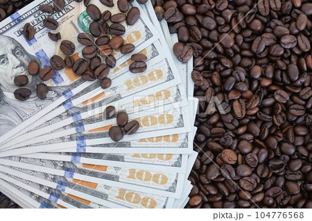 The 100 dollar bills are on roasted coffee beans. The concept of rising food prices, the global food crisis. The 100 dollar bills are on roasted coffee beans. The concept of rising food prices, the global food crisis. 104776568