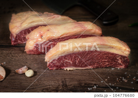 Organic machete or hanger butcher steak, near butcher knife with pink pepper and rosemary. Black background. Top view. side view Organic machete or hanger butcher steak, near butcher knife with pink pepper and rosemary. Black background. Top view. side view 104776680
