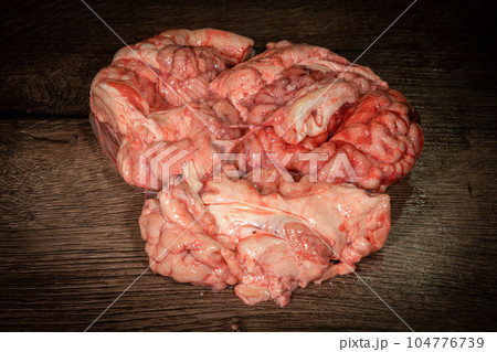 Pink brain raw before cooking on a wooden table. Raw fresh brain of a mammalian animal, a cow. Raw meat. Gut. Copy space 104776739