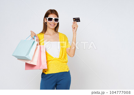 Happy young woman holding shopping bags and showing credit card isolated on white background. Happy young woman holding shopping bags and showing credit card isolated on white background. 104777008