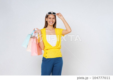 Portrait of excited emotional young woman wearing and touching sunglasses holding colorful shopping bags isolated on white background. Portrait of excited emotional young woman wearing and touching sunglasses holding colorful shopping bags isolated on white background. 104777011