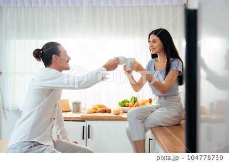 Happy married guy husband and girl wife drinking coffee celebrate at home 104778739