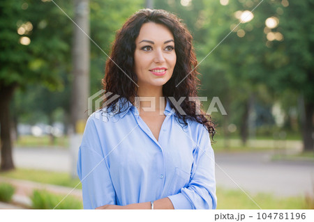 A beautiful smiling business woman in a blue shirt is walking down the alley in the city 104781196