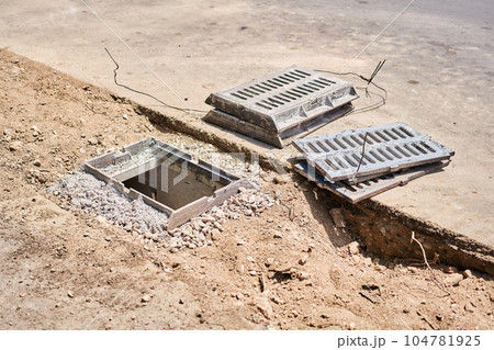 Laying concrete manholes and drain pipes for stormwater system. Connecting a trench drain to a concrete manhole structure at construction site. Construct stormwater and underground utilities 104781925