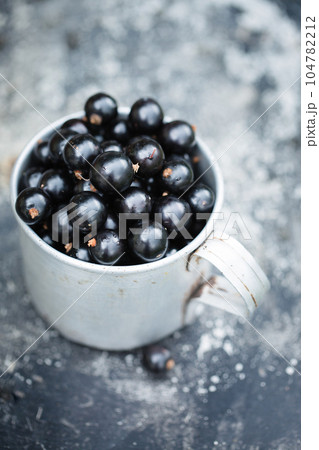 Ripe black currants in a metal vintage cup, top view Ripe black currants in a metal vintage cup, top view 104782212