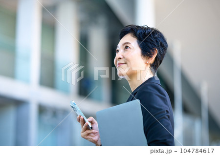 オフィスでスマホを持ったミドルビジネスウーマン オフィスでスマホを持ったミドルビジネスウーマン 104784617