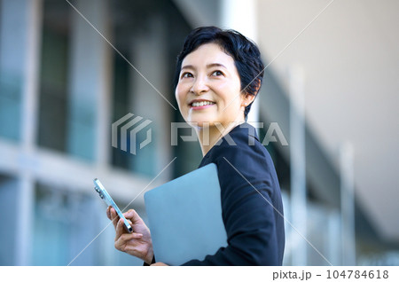 オフィスでスマホを持ったミドルビジネスウーマン オフィスでスマホを持ったミドルビジネスウーマン 104784618