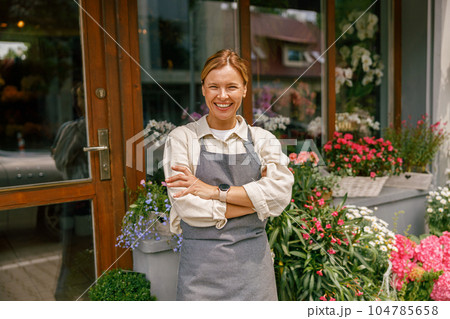 Smiling woman florist small business owner standing with crossed arms near own floral store 104785658