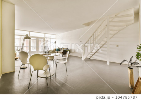 a living room with some chairs and a staircase leading up to the second floor in an apartment that has been painted white a living room with some chairs and a staircase leading up to the second floor in an apartment that has been painted white 104785787