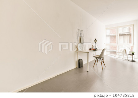 an empty living room with white walls and wood flooring, there is a small dining table in the corner an empty living room with white walls and wood flooring, there is a small dining table in the corner 104785818