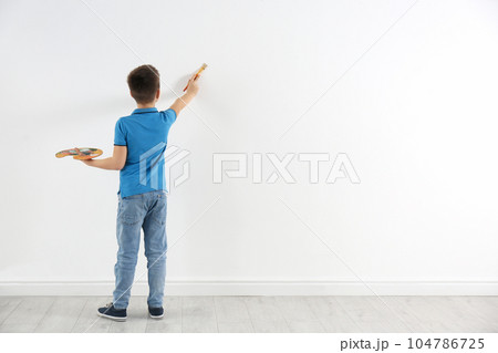 Little child painting on white wall indoors. Space for text 104786725