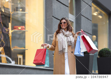 Beautiful young woman with shopping bags on city street Beautiful young woman with shopping bags on city street 104786947
