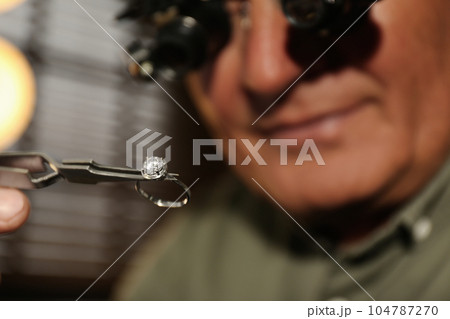 Professional jeweler working with beautiful ring indoors, closeup Professional jeweler working with beautiful ring indoors, closeup 104787270
