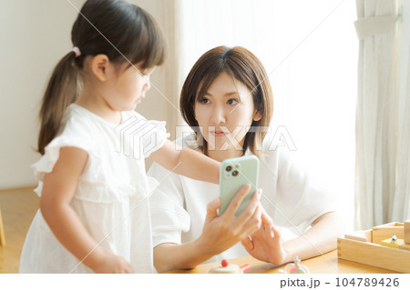 スマホを見るママと女の子の写真 104789426