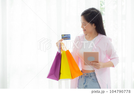 Young asian woman standing using digital tablet shopping online with credit card. 104790778