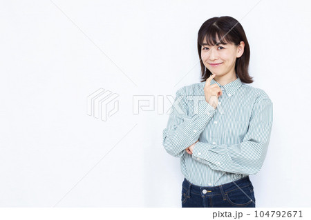 白い背景の前で笑顔で考えている30代の女性 白い背景の前で笑顔で考えている30代の女性 104792671