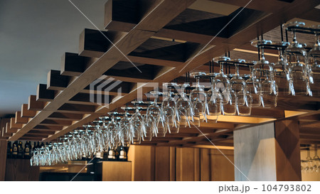Wine glasses hang above bar counter Wine glasses hang above bar counter 104793802