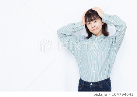 白い背景の前で頭を抱えて悩む30代の女性 104794043