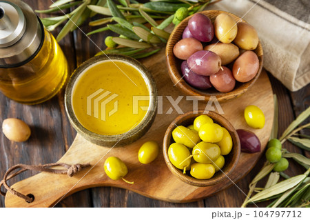 Freshly picked olives berries in wooden bowls and pressed oil served on old wooden boards. Freshly picked olives berries in wooden bowls and pressed oil served on old wooden boards. 104797712