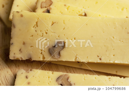 Sliced piece of milk cheese with walnuts Sliced piece of milk cheese with walnuts 104799686
