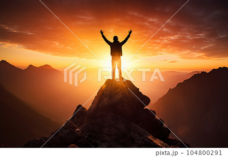 The silhouette of a tourist standing with his arms outstretched the golden glow of the morning sun on the mountaintop. Standing up to achieve success. 104800291