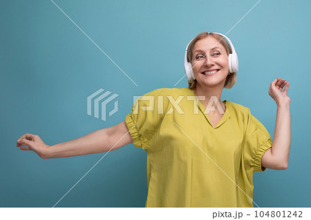 portrait of a blond adult woman dancing to her playlist listening to music in headphones portrait of a blond adult woman dancing to her playlist listening to music in headphones 104801242