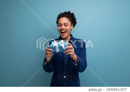 young happy woman with dark skin and black curly hair dressed in a blue denim suit is happy to young happy woman with dark skin and black curly hair dressed in a blue denim suit is happy to 104801307