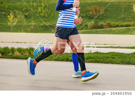 two male athletes runners running together marathon race in landscape park, summer sports event 104801950