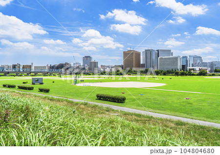 青空広がる多摩川緑地と川崎駅前のビル群【神奈川県・川崎市－東京都・大田区】 104804680