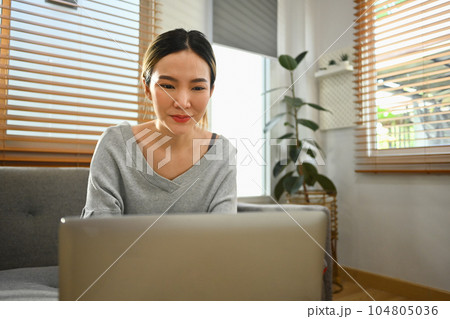 Happy young woman using laptop at home, chatting with friends in social network, watching movie and shopping online Happy young woman using laptop at home, chatting with friends in social network, watching movie and shopping online 104805036