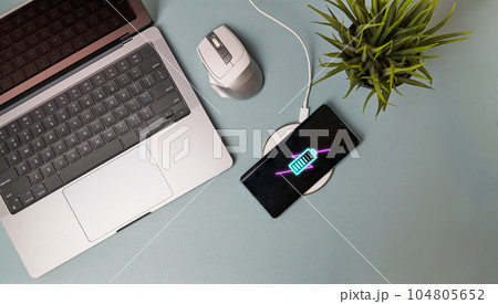 Charging mobile phone battery with wireless charging device on the table. Charging mobile phone battery with wireless charging device on the table. 104805652
