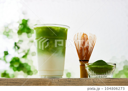 抹茶ラテ、氷の入ったミルクに抹茶を注ぎ入れる 抹茶ラテ、氷の入ったミルクに抹茶を注ぎ入れる 104806273