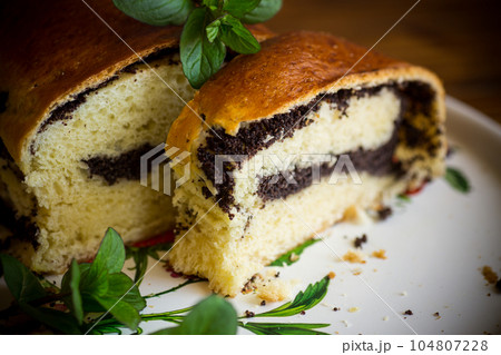 roll with poppy seeds inside on a wooden table. 104807228