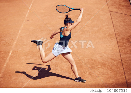 Dynamic image of professional athlete, tennis player in motion during game playing, training outside on warm sunny day 104807555