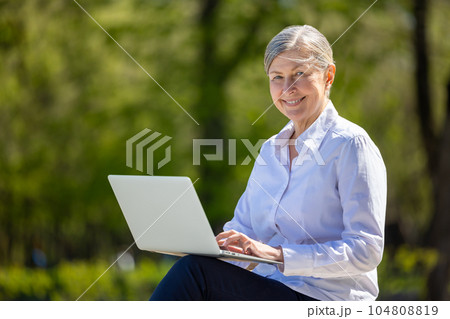 Business woman with laptop sitting on the bench in the park Business woman with laptop sitting on the bench in the park 104808819