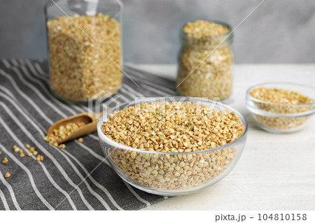 Uncooked green buckwheat grains in bowl on white wooden table Uncooked green buckwheat grains in bowl on white wooden table 104810158