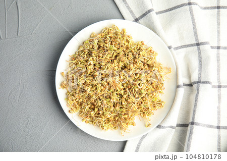 Plate with sprouted green buckwheat on light grey table, top view 104810178