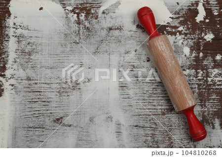 Flour and rolling pin on wooden table, top view. Space for text 104810268