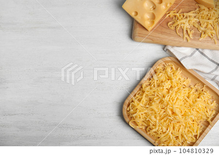 Flat lay composition with grated cheese on white wooden table. Space for text Flat lay composition with grated cheese on white wooden table. Space for text 104810329