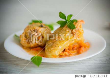 stewed in gravy stuffed peppers in a plate on a wooden table 104810741