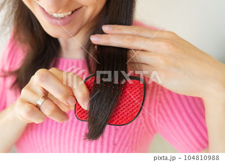 Portrait of a radiant girl combing her dark hair, looking away with a calm smile. Hair care concept. Portrait of a radiant girl combing her dark hair, looking away with a calm smile. Hair care concept. 104810988