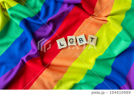 Rainbow flag of the LGBT community. Equal rights for all. Gender identity of different people, inscription with wooden letters LGBT. 104810989