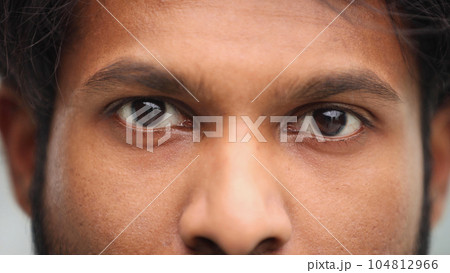 young beautiful man with brown eyes looks at the camera. 104812966