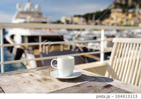 Cup of coffee on a wooden table on balcony hotel in Principality of Monaco. Cup of coffee on a wooden table on balcony hotel in Principality of Monaco. 104813113