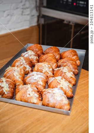 Sprinkle the finished croissants on a baking sheet with almond flakes and powdered sugar 104813141