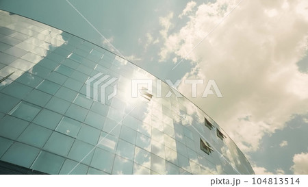 Modern glass facade of an office building with open windows reflects sun, sky and clouds. Business opportunity concept 104813514