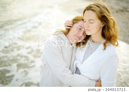 Redhead senior mother and her beautiful adult daughter are walking together and embracing. Family relationships between adult children and older parents 104813721