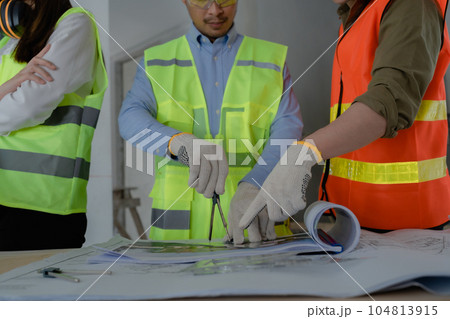 multi ethnic engineer brainstorming and measuring for cost estimating on paperworks and floor plan drawings about design architectural and engineering for houses and buildings. 104813915